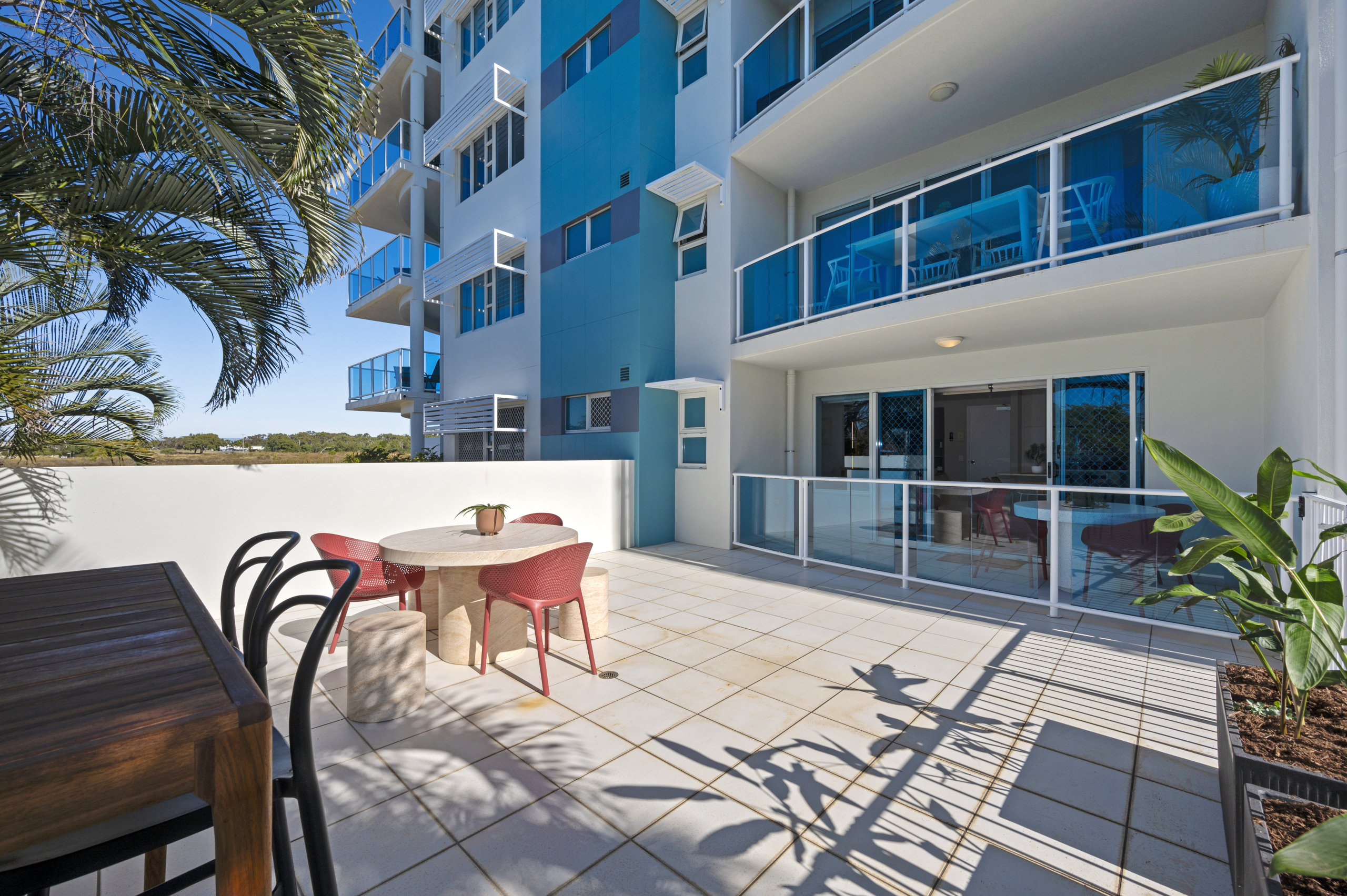 Sunlit patio of Koola Palms 101 with the Koola Beach Apartments building behind