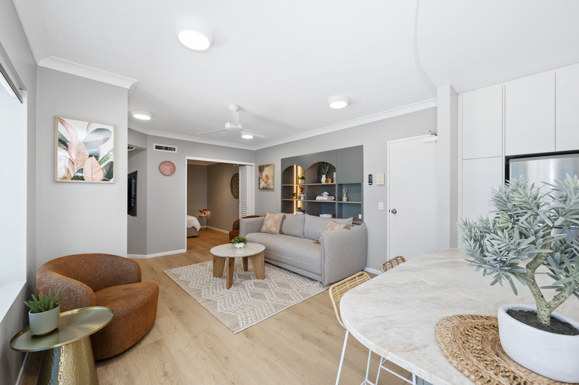 Koola Palms 101 open plan living room with grey sofa, tan leather armchair, round marble dining table and renovated kitchen